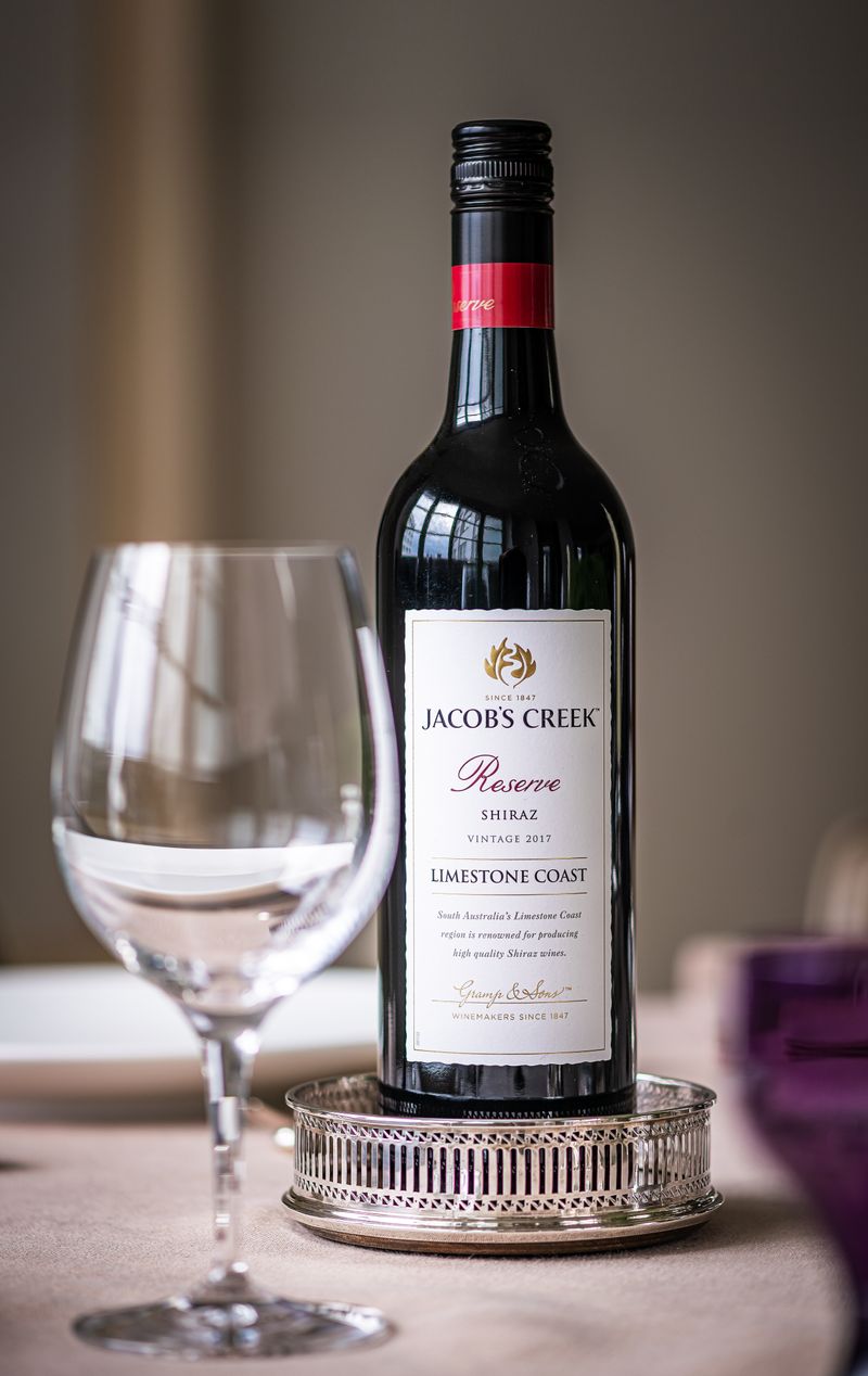 Copas de vino tinto sobre un mantel de lino junto a una mesa puesta